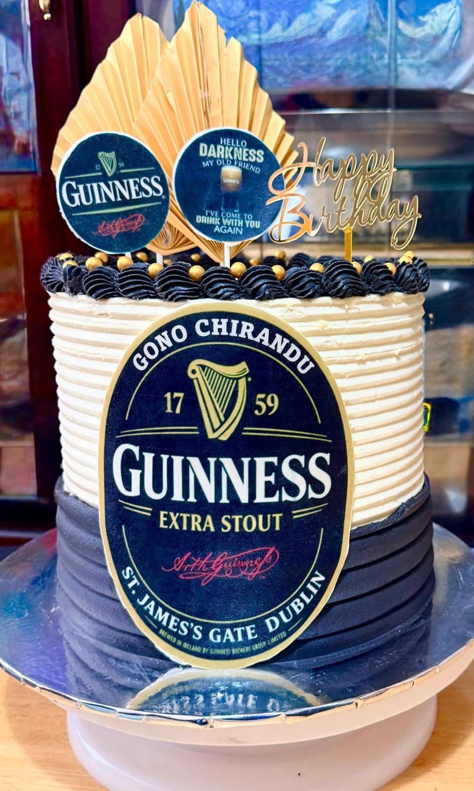 A navy and ivory birthday cake themed around a favourite stout, topped with a gold fan
